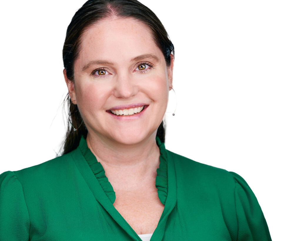 Professional headshot of a smiling businesswoman wearing a green blouse against a bright white background in St. Louis, Missouri.