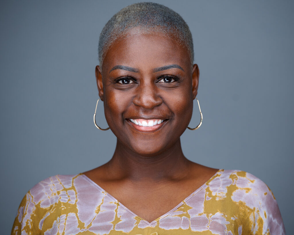 Professional headshot of a smiling woman against a gray studio background in St. Louis